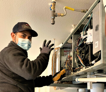 Technician wearing safety equipment servicing an air conditioning unit.