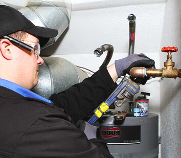 Employee fixing a water heater with a wrench