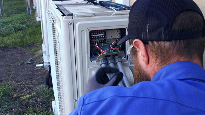 hvac tech repairing unit and performing HVAC repair services 