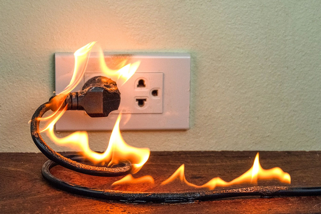 Cord plugged into an electrical outlet that's on fire