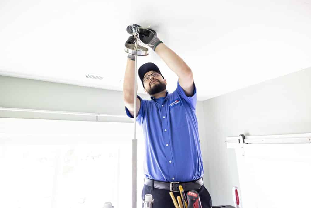 24/7 electrician performing electrical services installing a new ceiling light