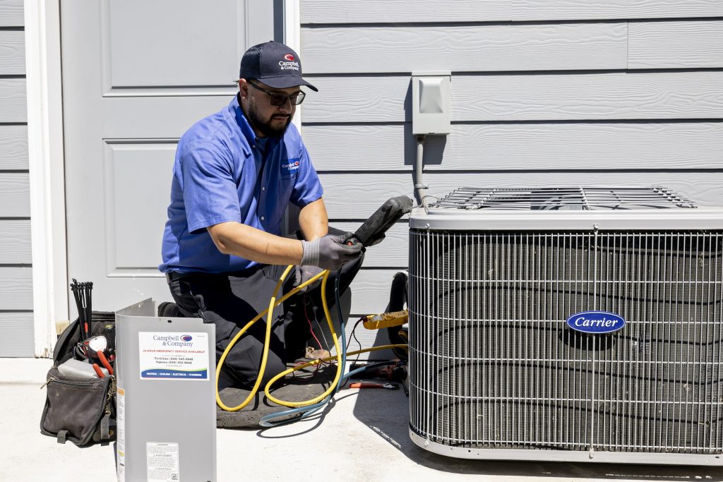 A service technician performing a tune-up on a Carrier AC unit.