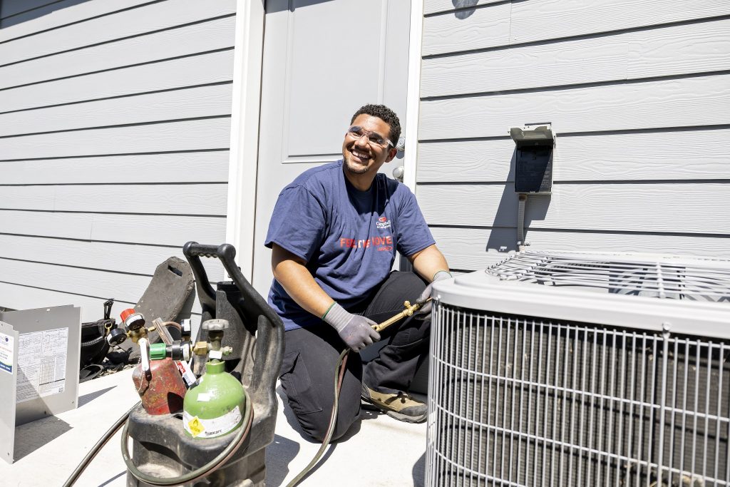 air conditioning technician smiling while installing a heat pump