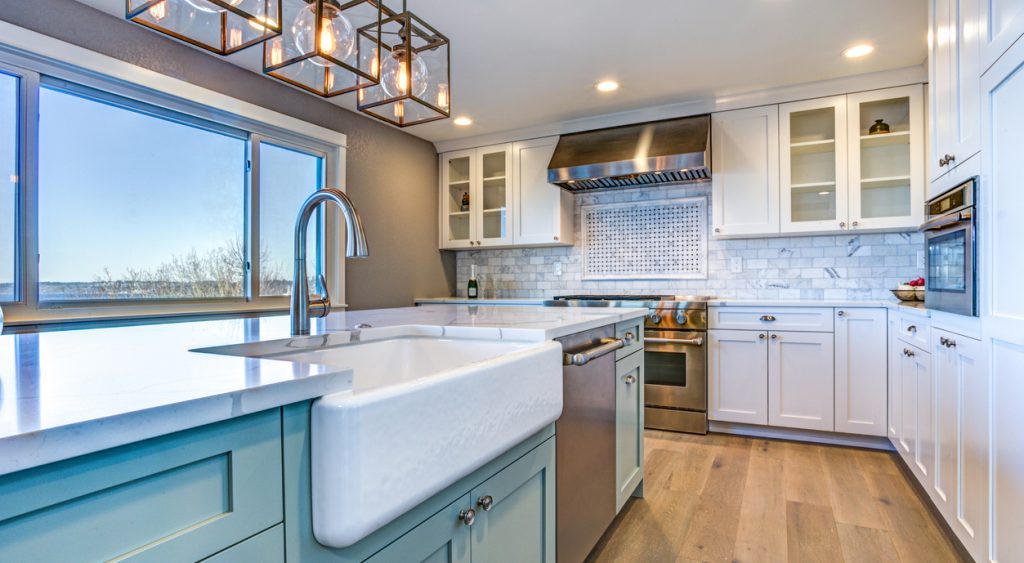 Beautiful kitchen room with green island, farmhouse sink, and stainless steel dishwasher