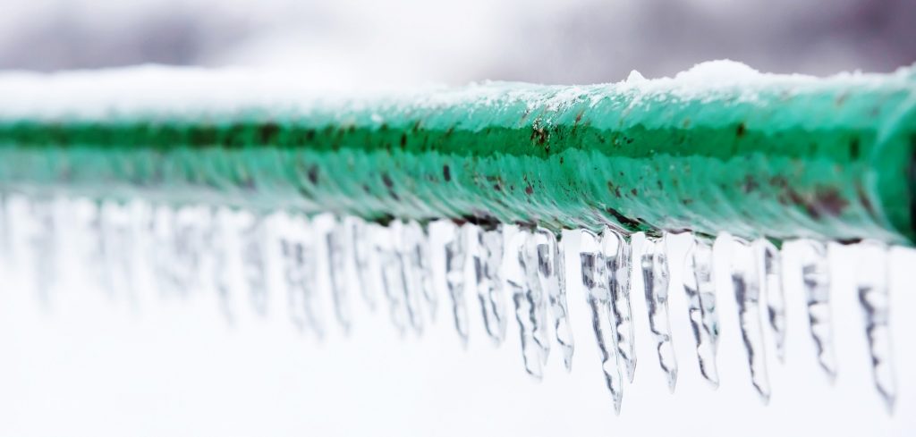 Frozen pipe with frost and icicle drips