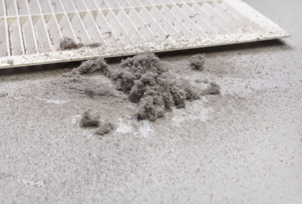 Pile of dust next to an air vent that has been cleaned