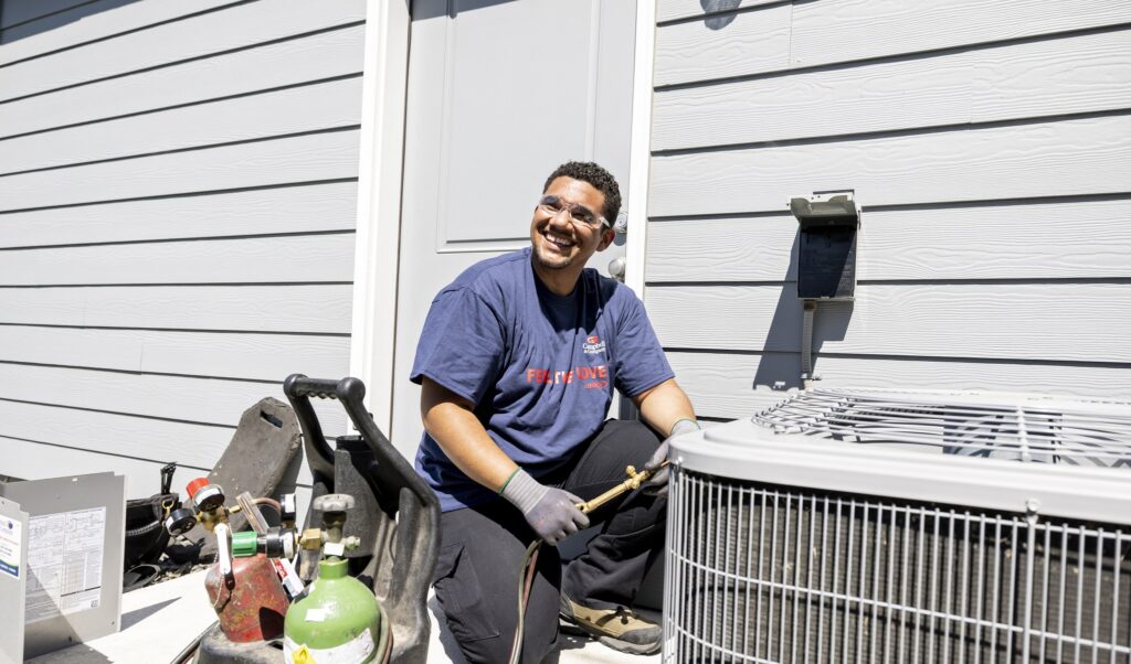 Air conditioner technician smiling while installing a heat pump